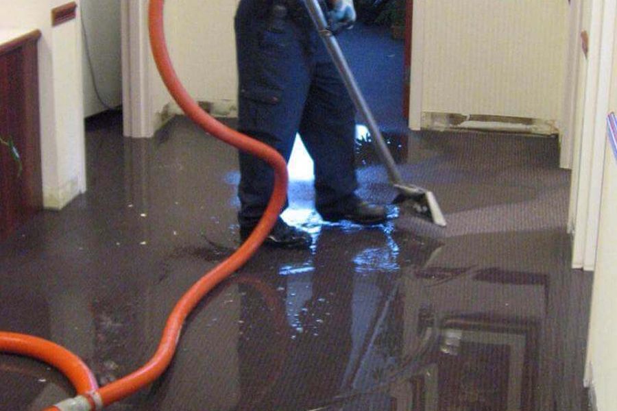Water being vacuumed from a hallway floor after a leak