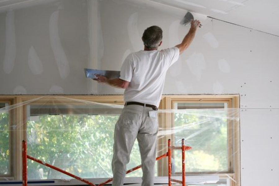 Contractor finishing drywall during interior restoration